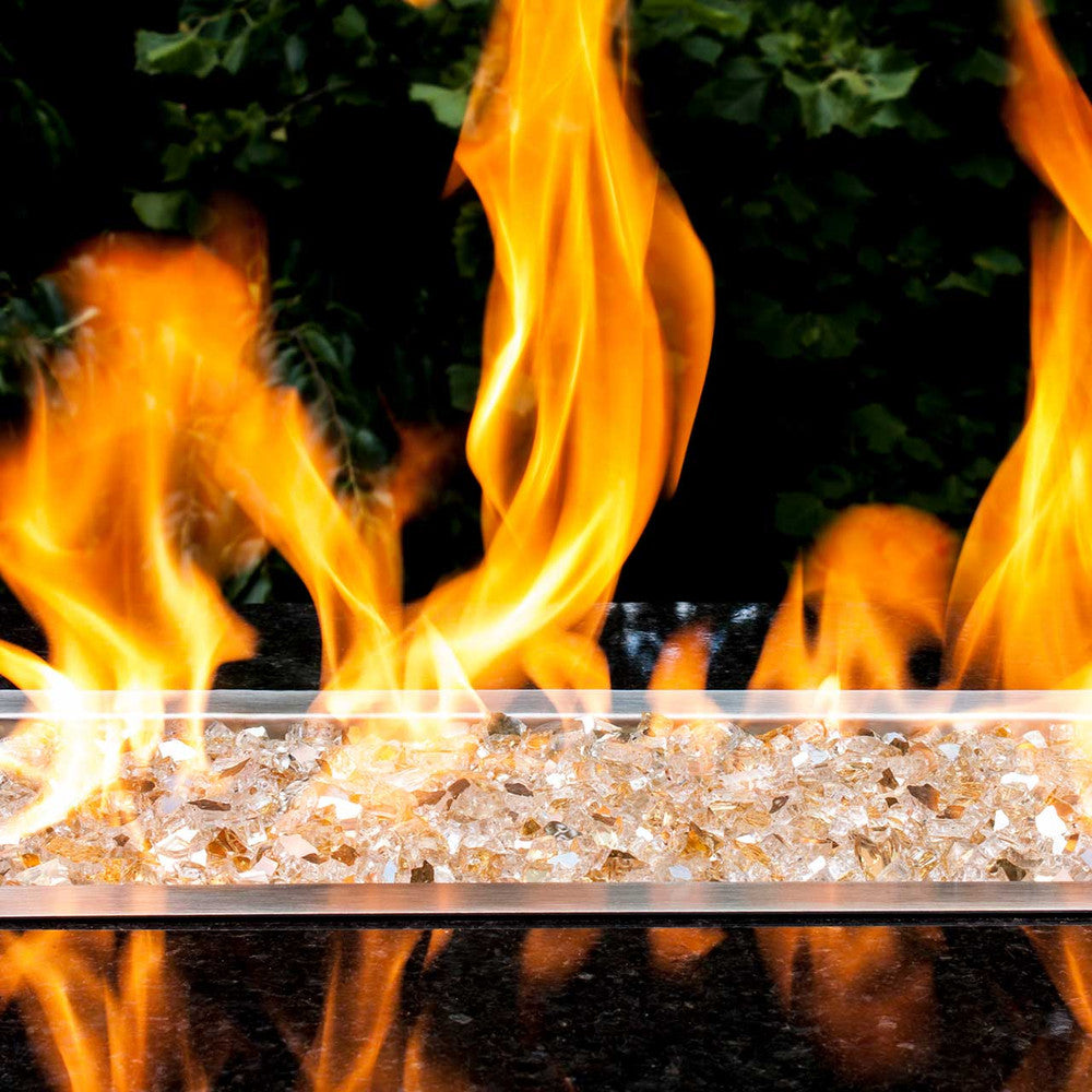 Horizontal angle of flames dancing over glittering yellow gold fire glass pieces