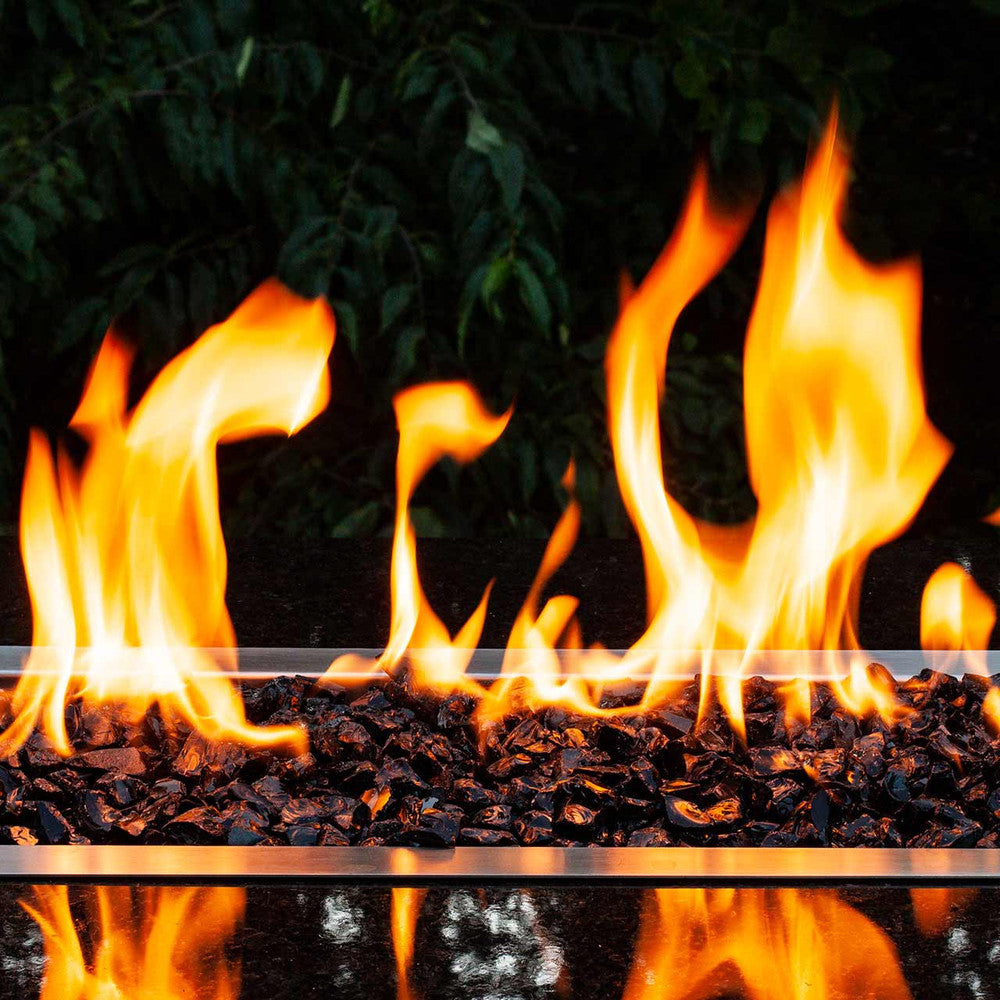 Horizontal view of jet black crushed fire glass in a gas fire pit